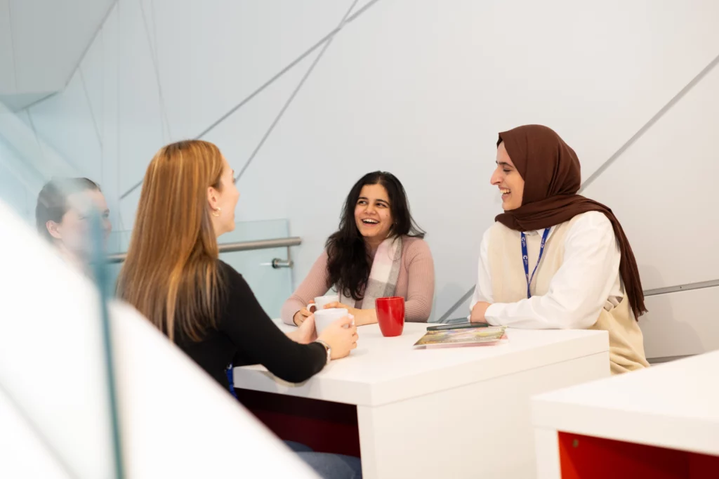 PhD Students sitting at a table and discussing their research