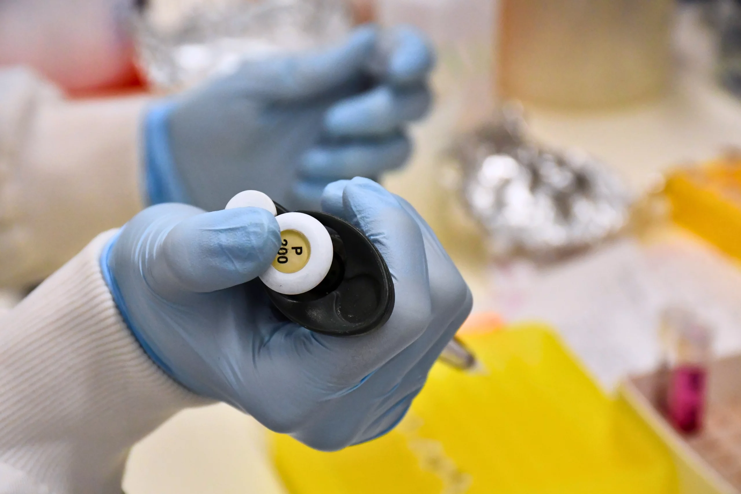 Gloved hands holding a p200 pipette